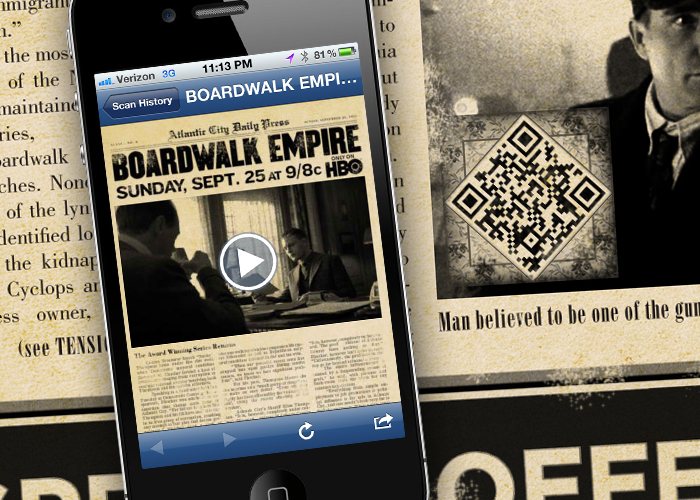 Phone scanning the newspaper's QR code to reveal a Boardwalk Empire video