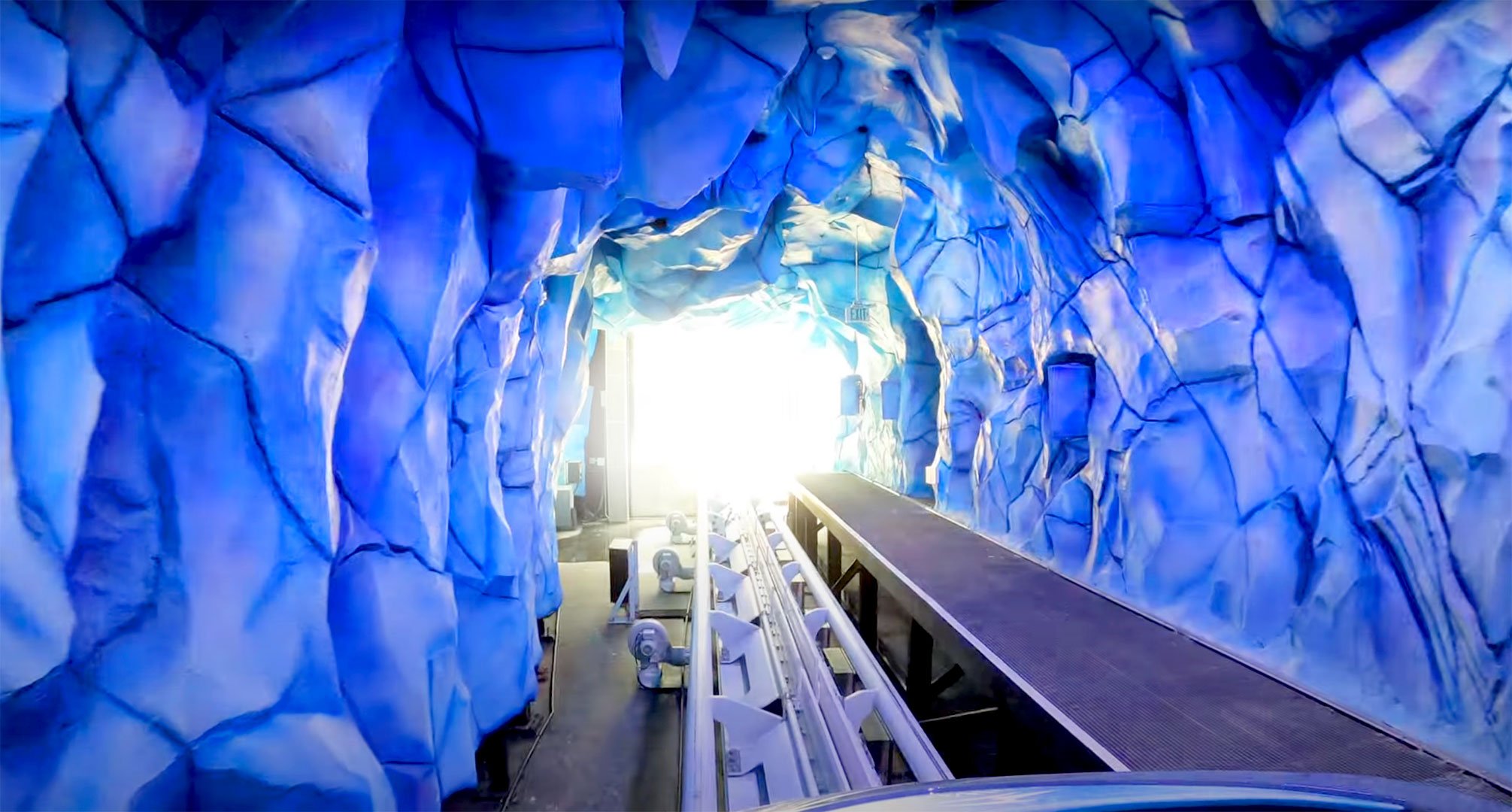 Illuminated blue ice tunnel along the coaster track