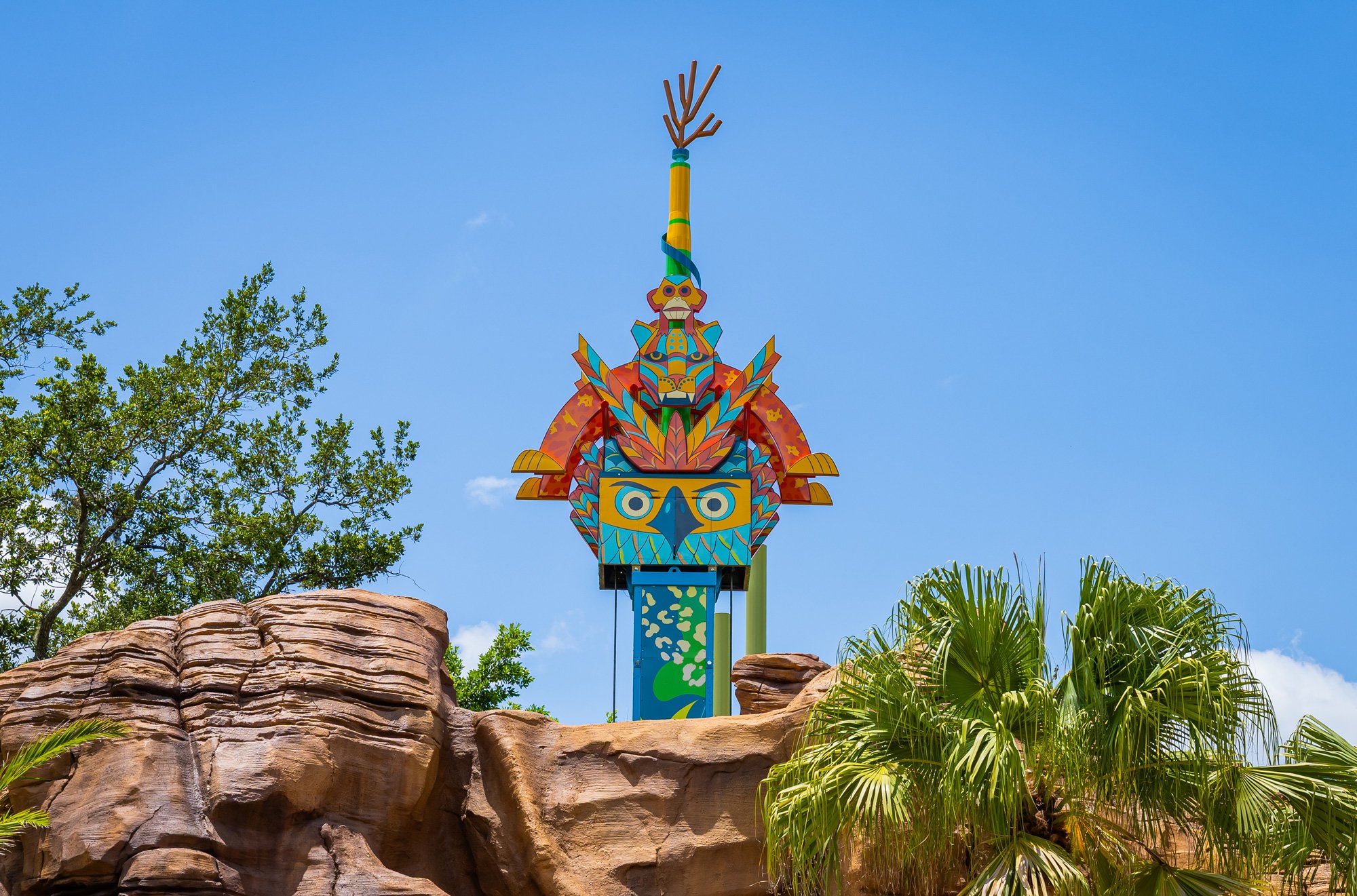 Top of the Treetop Drop tower rising above the themed rockwork